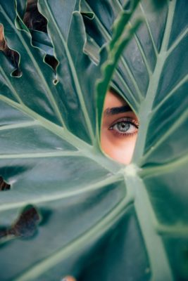 woman looking through leaf